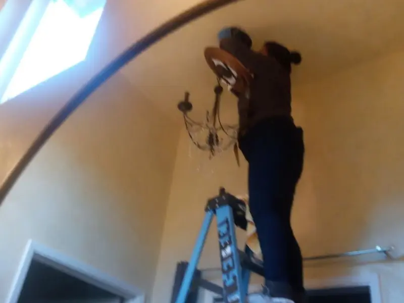 Electrician installing a chandelier in a Riviera Beach residence